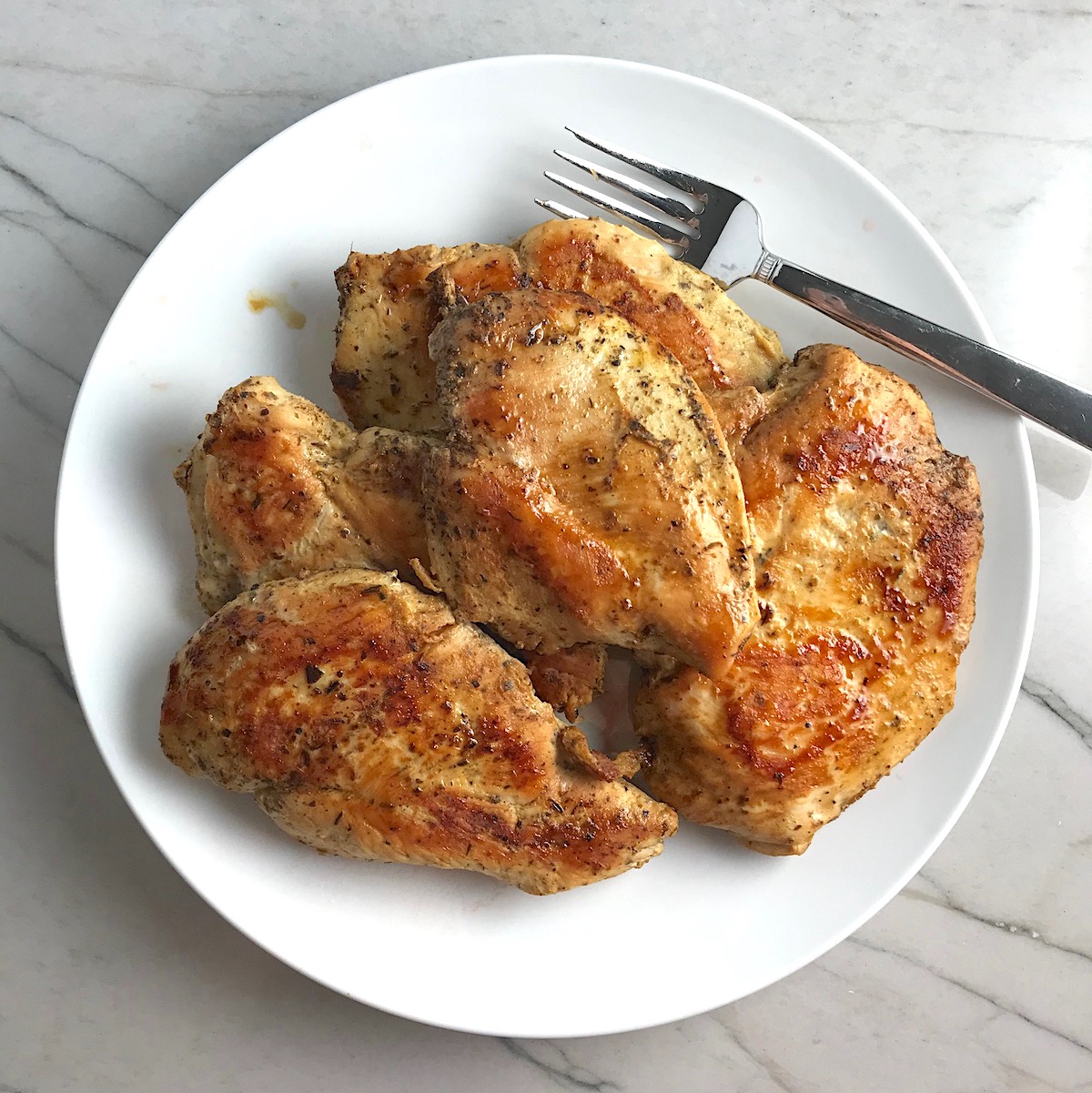 Cooked chicken breasts on plate for article How long to bake chicken breasts at 425