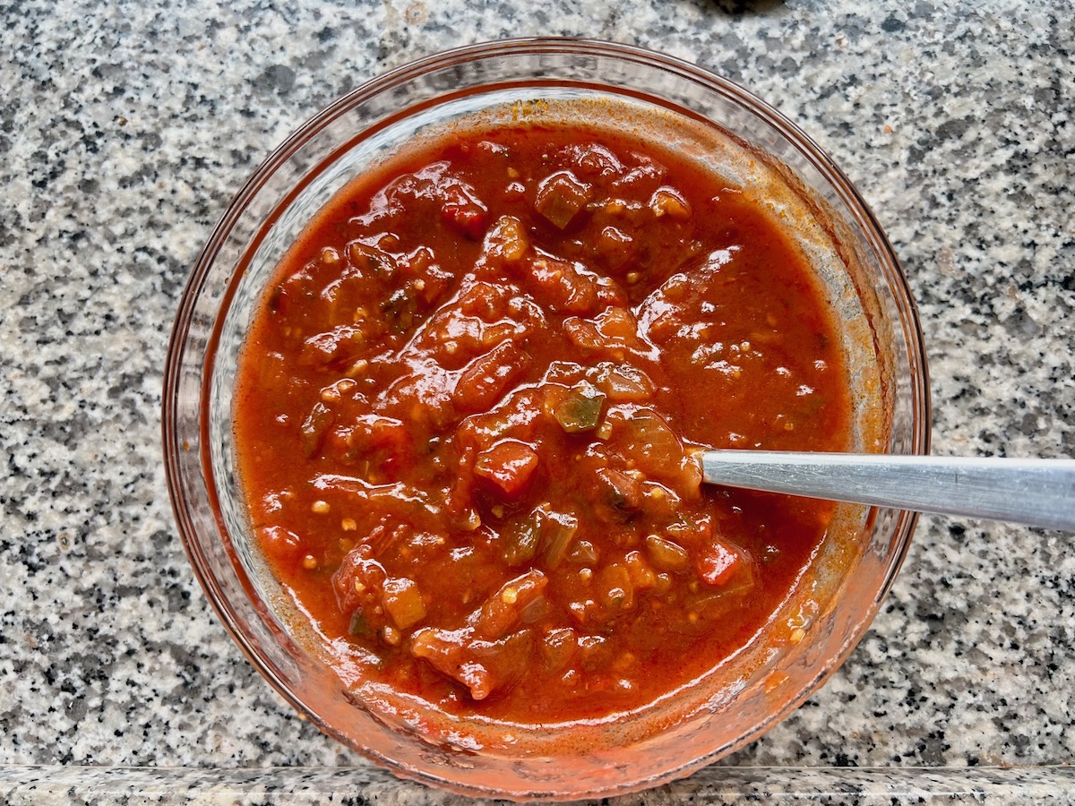 Chunky tomato salsa in a bowl with spoon for Salsa Chicken Casserole Recipe.