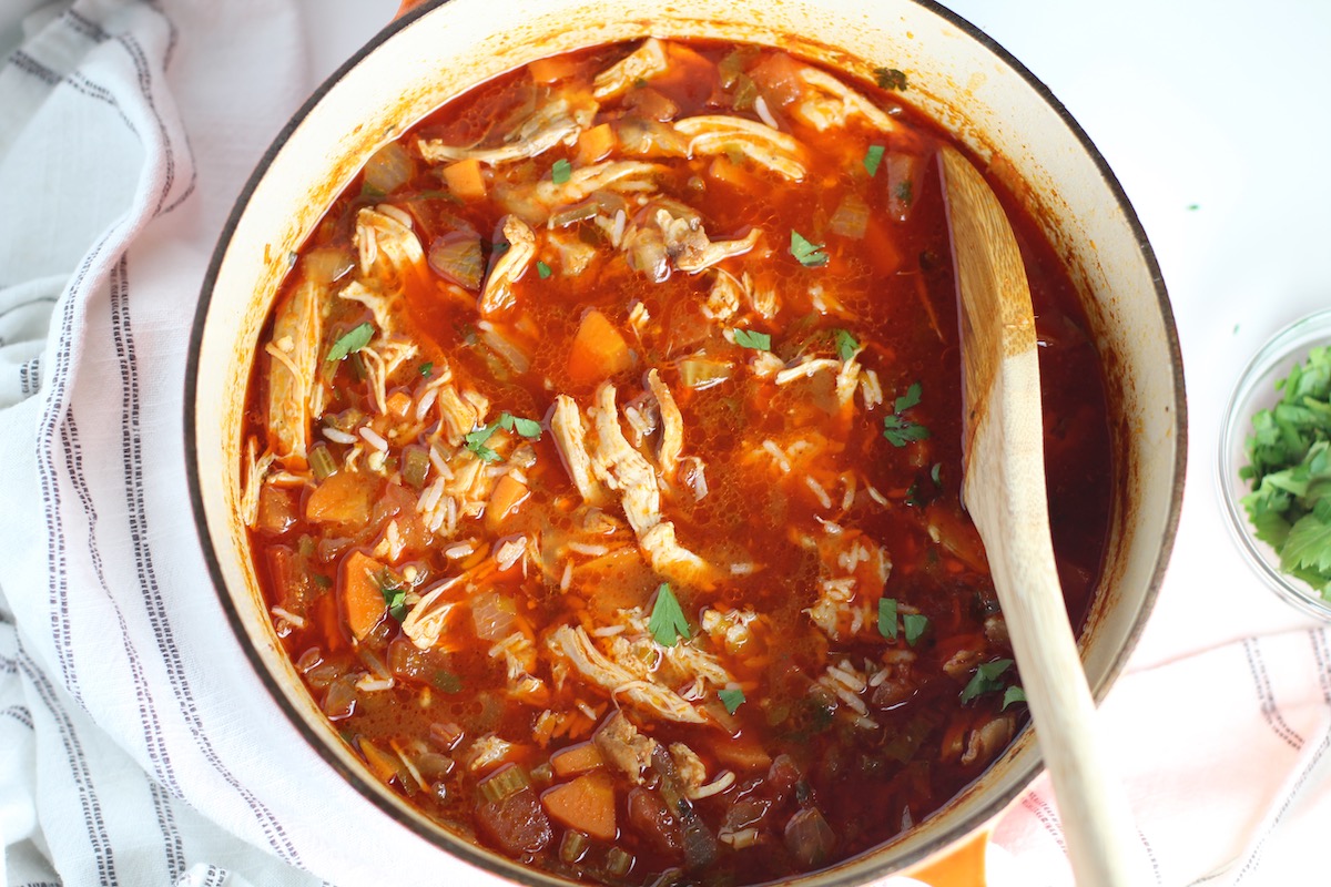 Spanish Chicken Soup in a pot with a wooden spoon on table.