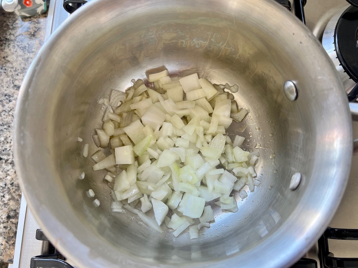 Diced onions in a small pot cooking for crockpot white chicken enchilada casserole.