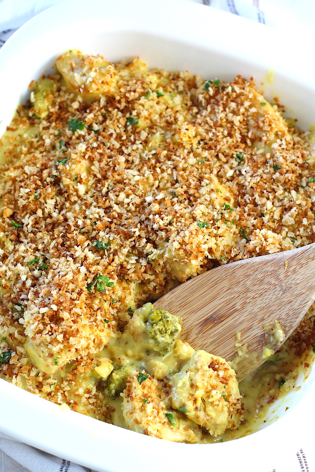 Wooden Spatula scooping the corner of Chicken Divan Curry Casserole Recipe from the casserole dish.