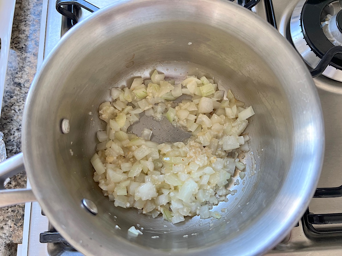 Diced onions and minced garlic cooking in oil in a sauce pot for Low carb Cauliflower Rice and Chicken Casserole.