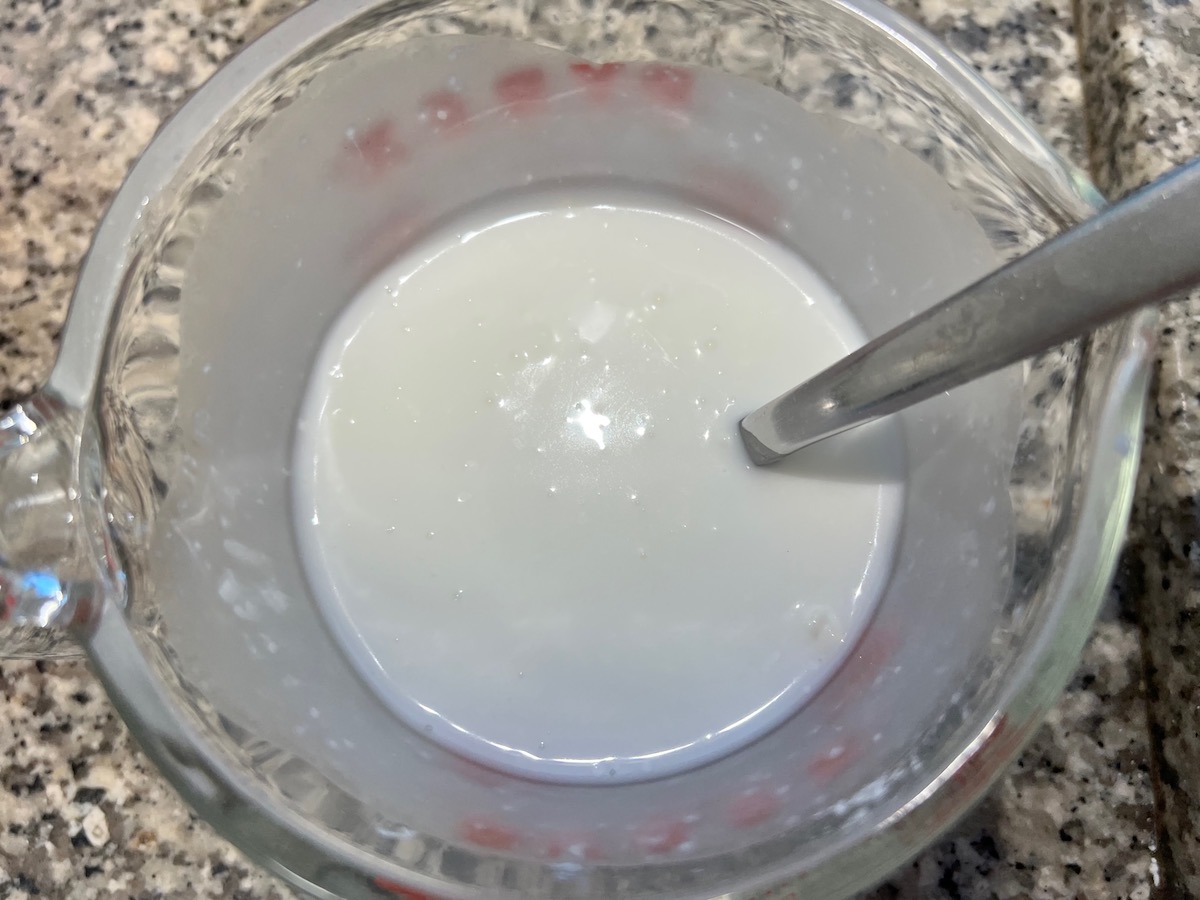 Cornstarch and Coconut slurry in a measuring cup with fork for Crockpot Thai Chicken Curry recipe.
