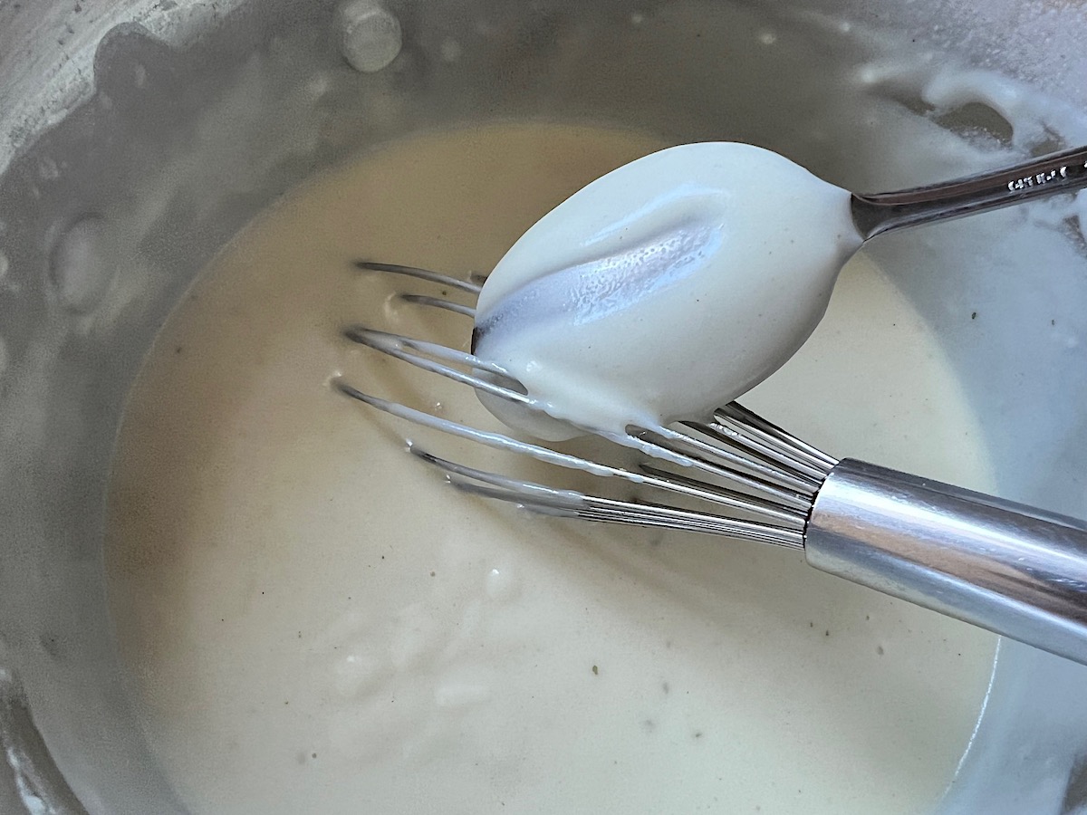 Whisk in a saucepan mixing milk into the flour and butter roux for Broccoli and Chicken Lasagna recipe.