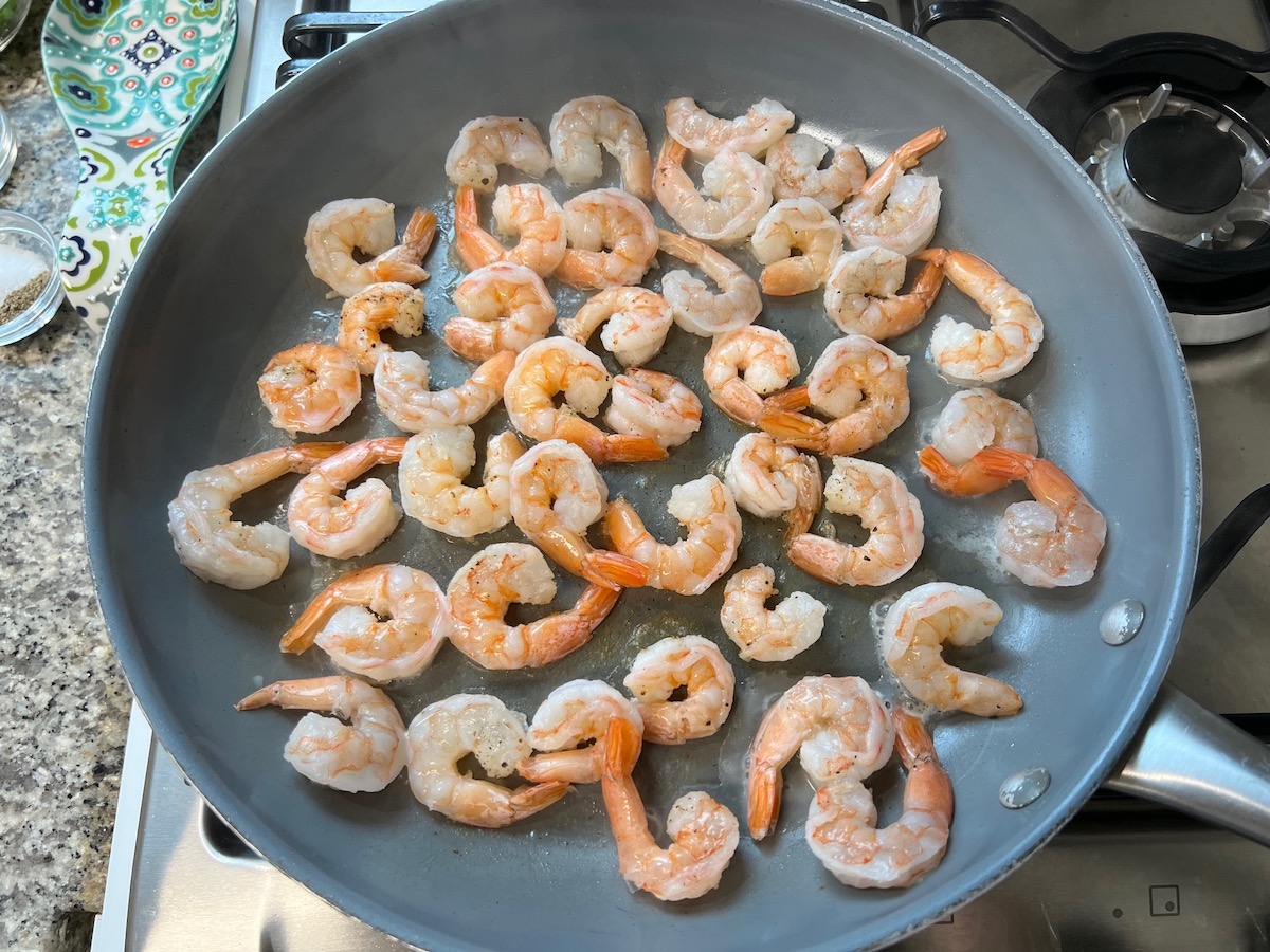 Shrimp with tails on cooking in a frying pan for Shrimp and Chicken Fried Rice recipe.