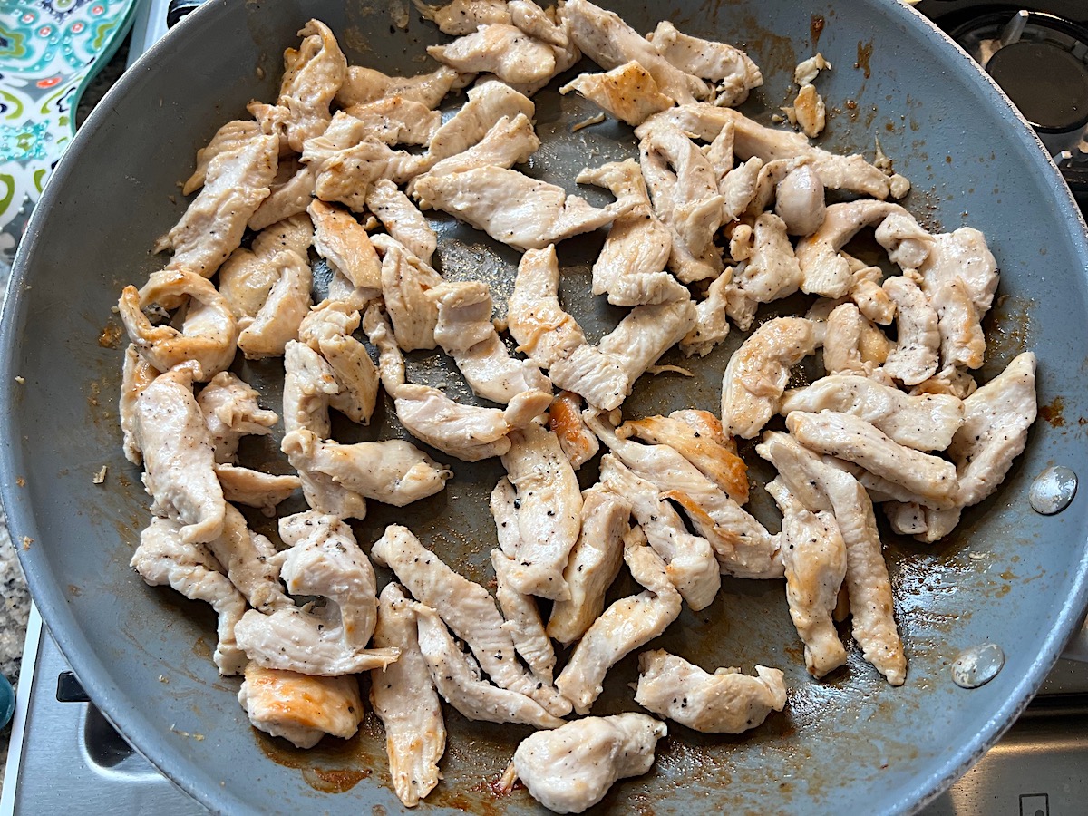 Chicken strips cooking in a frying pan for Shrimp and Chicken Fried Rice recipe.
