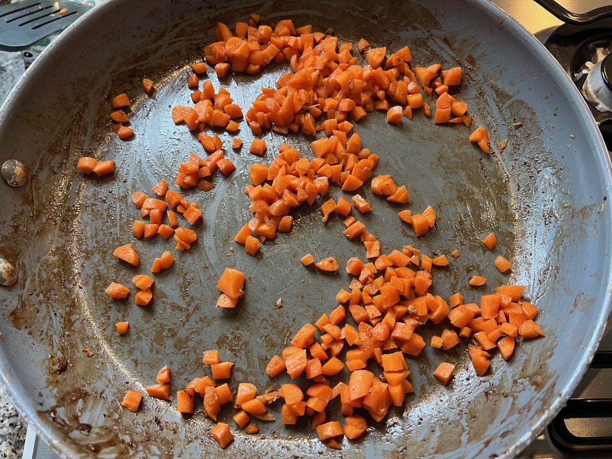 Diced carrots cooking in a frying pan for Shrimp and Chicken Fried Rice recipe.