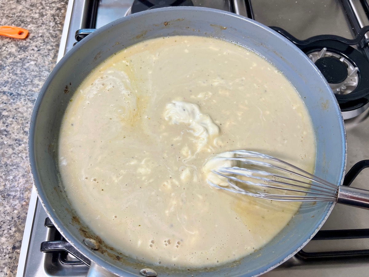 Whisk mixing in sour cream to thickened butter, flour, and broth sauce for Cheesy Hamburger Tater Tot Casserole Recipe.