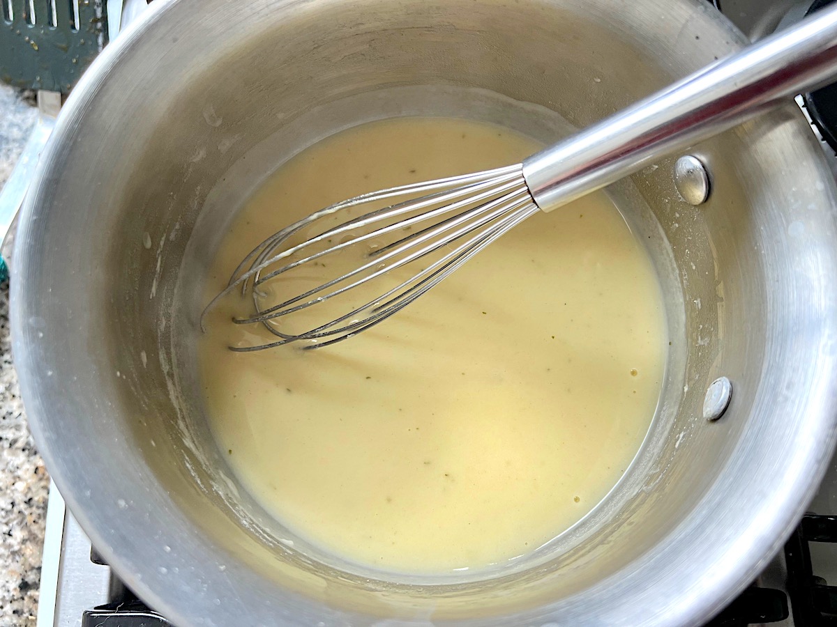 Whisk mixing sauce in a pot for the Creamy chicken piccata Casserole recipe.