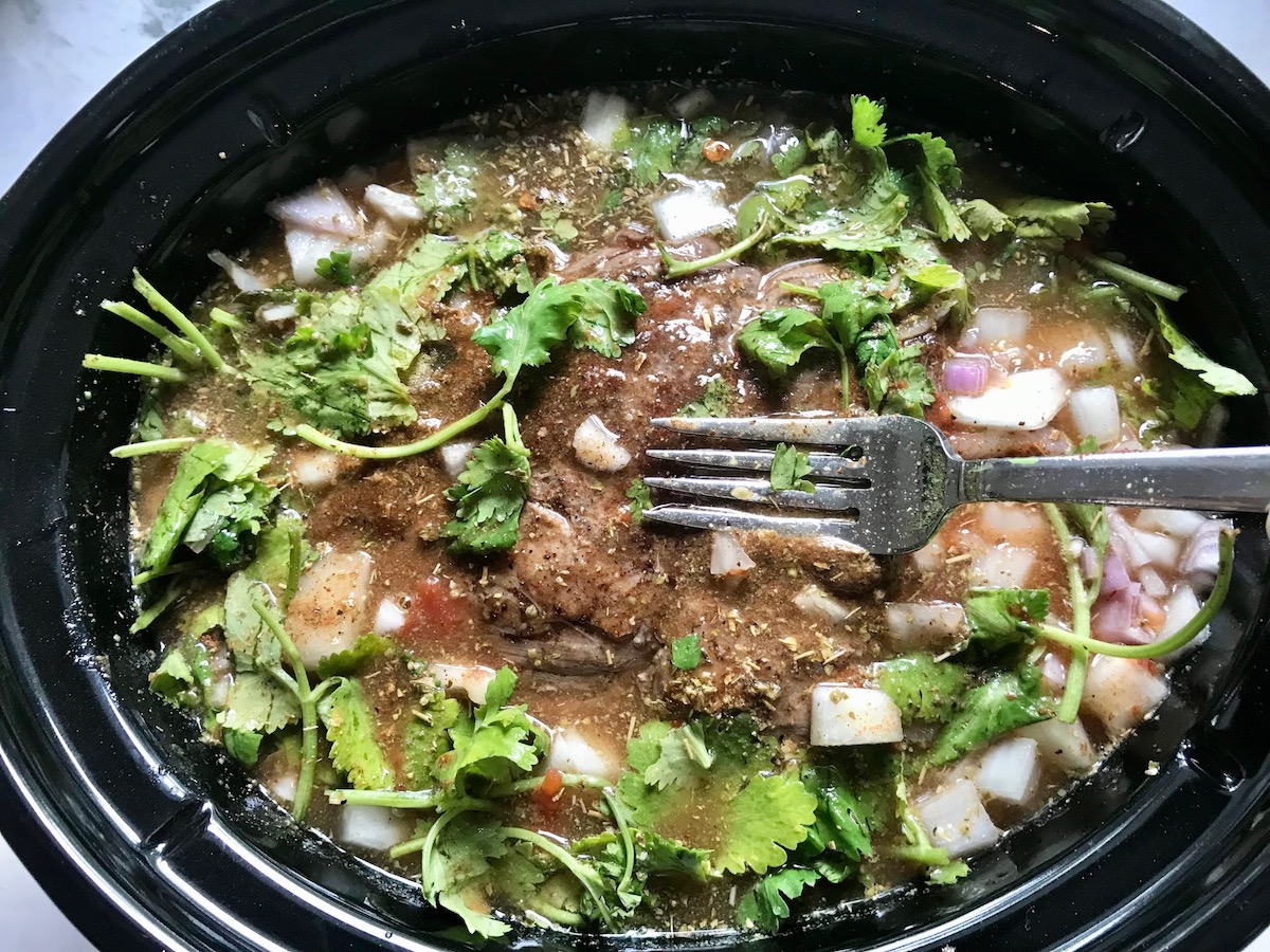 Beef chuck roast topped with beef broth, diced onions, tomato paste, herbs, and seasonings before being slow cooking for Birria Nachos.