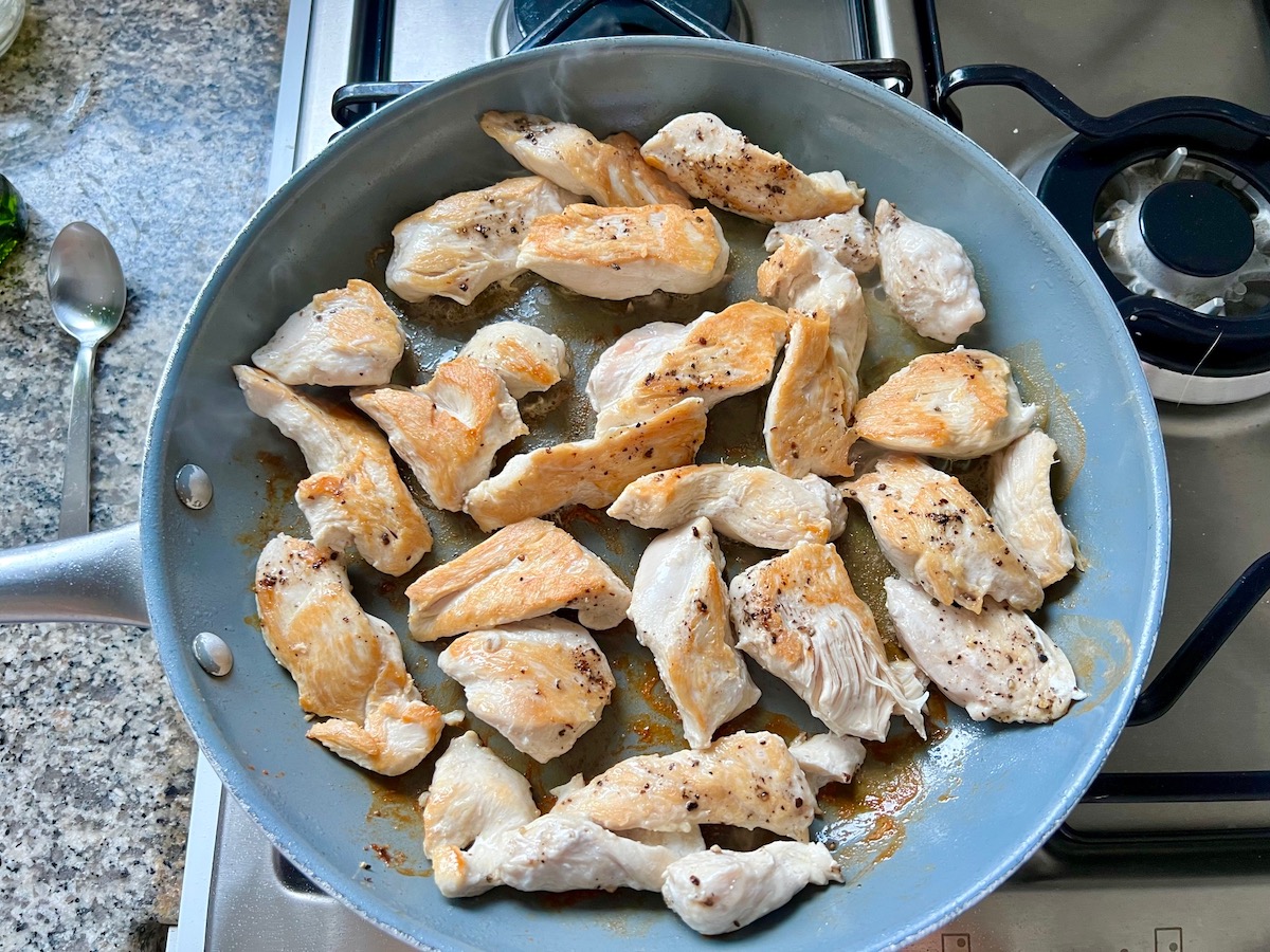 Chicken bites seared to a golden brown in a skillet.