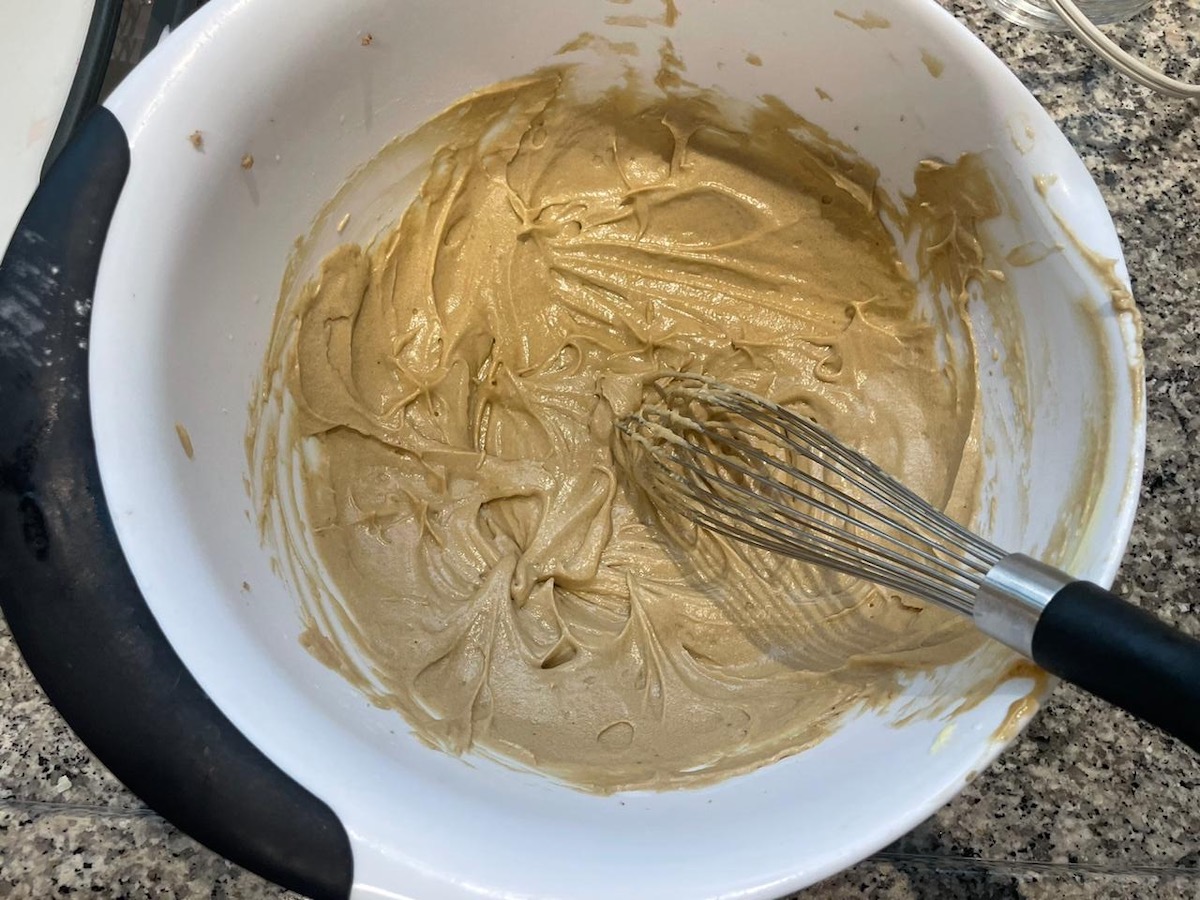 Batter being mixed with a whisk in a large bowl for the Strawberry Banana Cake recipe.