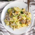 Creamy Fettuccine Pasta with Zucchini and Mushrooms and parmesan cheese shredded on top, all on a plate with a fork.