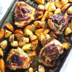 Tray baked Chicken Thighs and Potatoes on the pan perfectly browned glistening.
