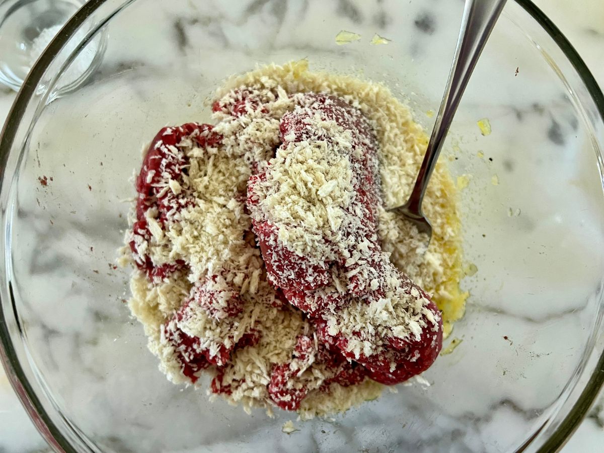 Ground beef and breadcrumbs added to the onion mixture in a mixing bowl.