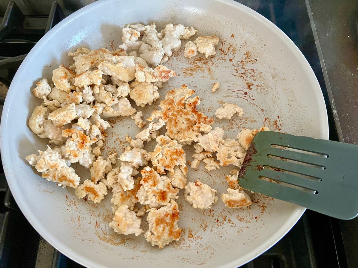 Browned ground chicken cooking in a skillet.