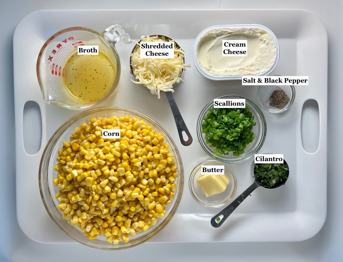 Ingredients measured out in bowls on white tray and labels overlayed onto the image for each ingredient for Creamy Mexican Street Corn Casserole recipe.