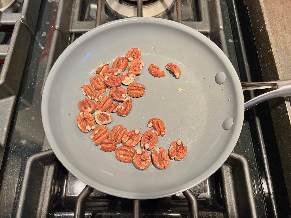 Walnuts toasting in a pan on the stove for Pesto Pasta with Tomatoes.