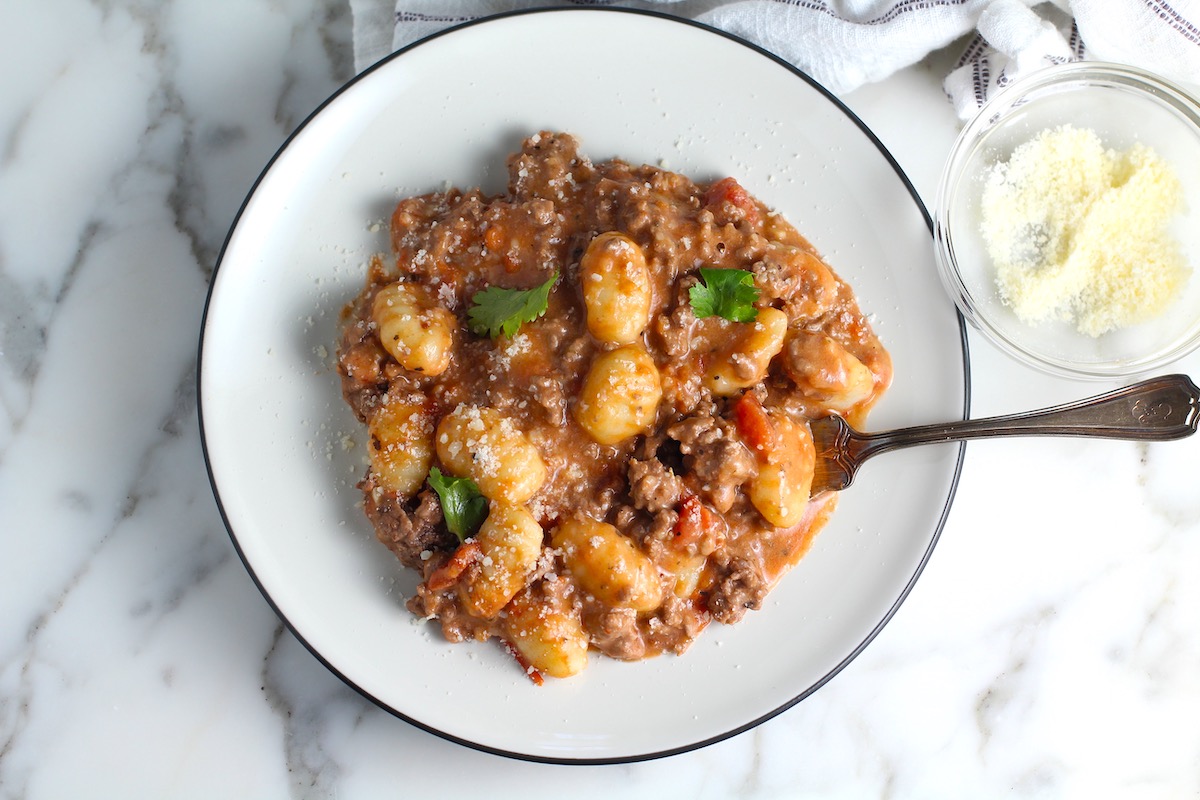 Ground Beef Gnocchi Skillet recipe on a plate with fresh parsley garnish and a fork.