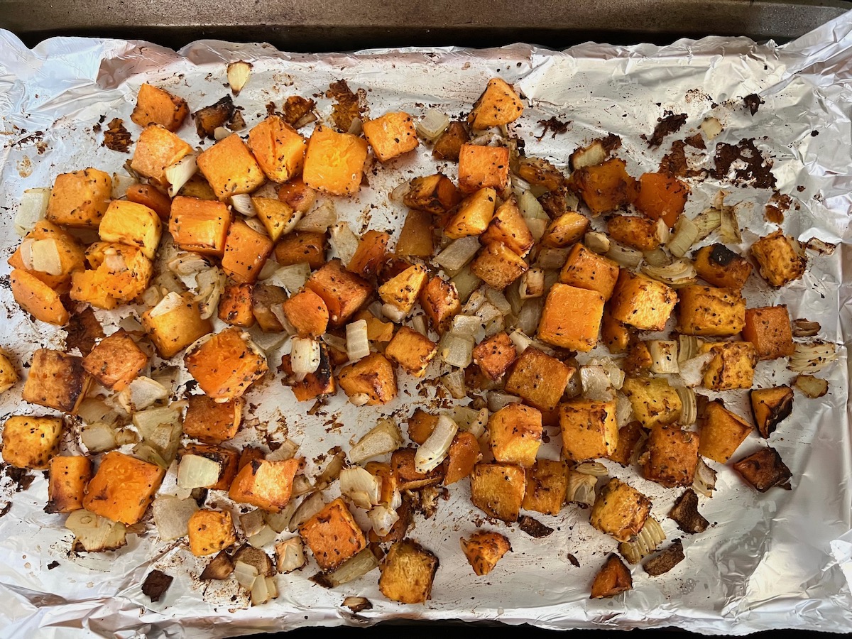 Butternut Squash cubes, diced onions, and seasonings roasted on an aluminum foil lined sheet pan for the Butternut Squash Spaghetti recipe.