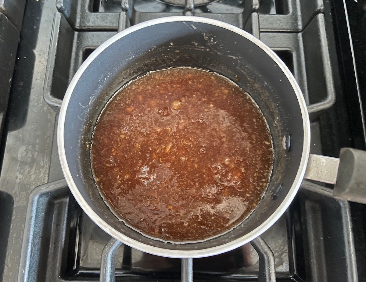 All ingredients mixed and cooked in a saucepan on the stove for the Apricot Sauce Wings recipe.
