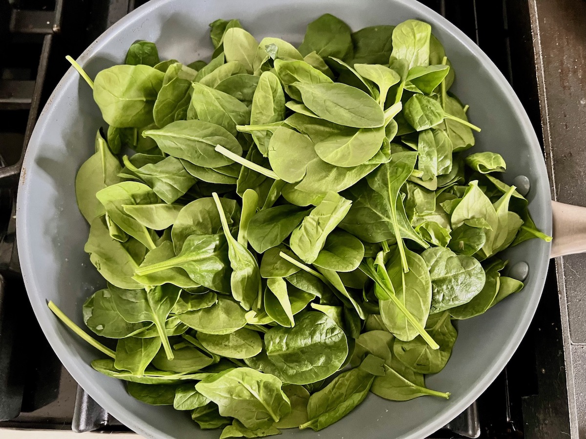 Fresh baby spinach leaves in a pan before being wilted down for Chicken Ricotta Pasta Recipe.