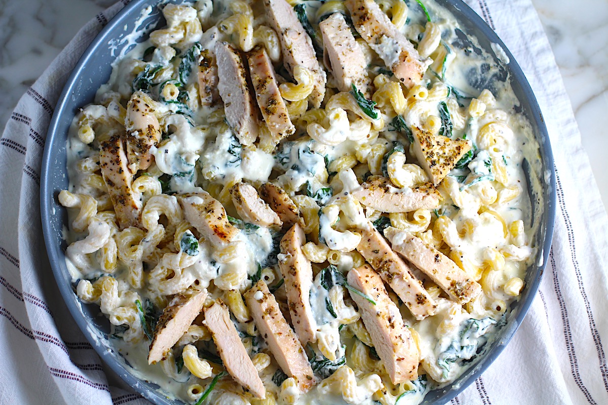 Chicken Ricotta Pasta in a large frying pan with spinach cooked and mixed in and the chicken sliced and laying on top.