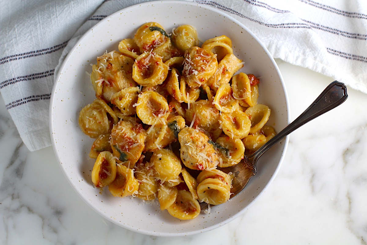 Creamy Sun Dried Tomato Sauce with Chicken and Pasta on a high rimmed plate with fork.