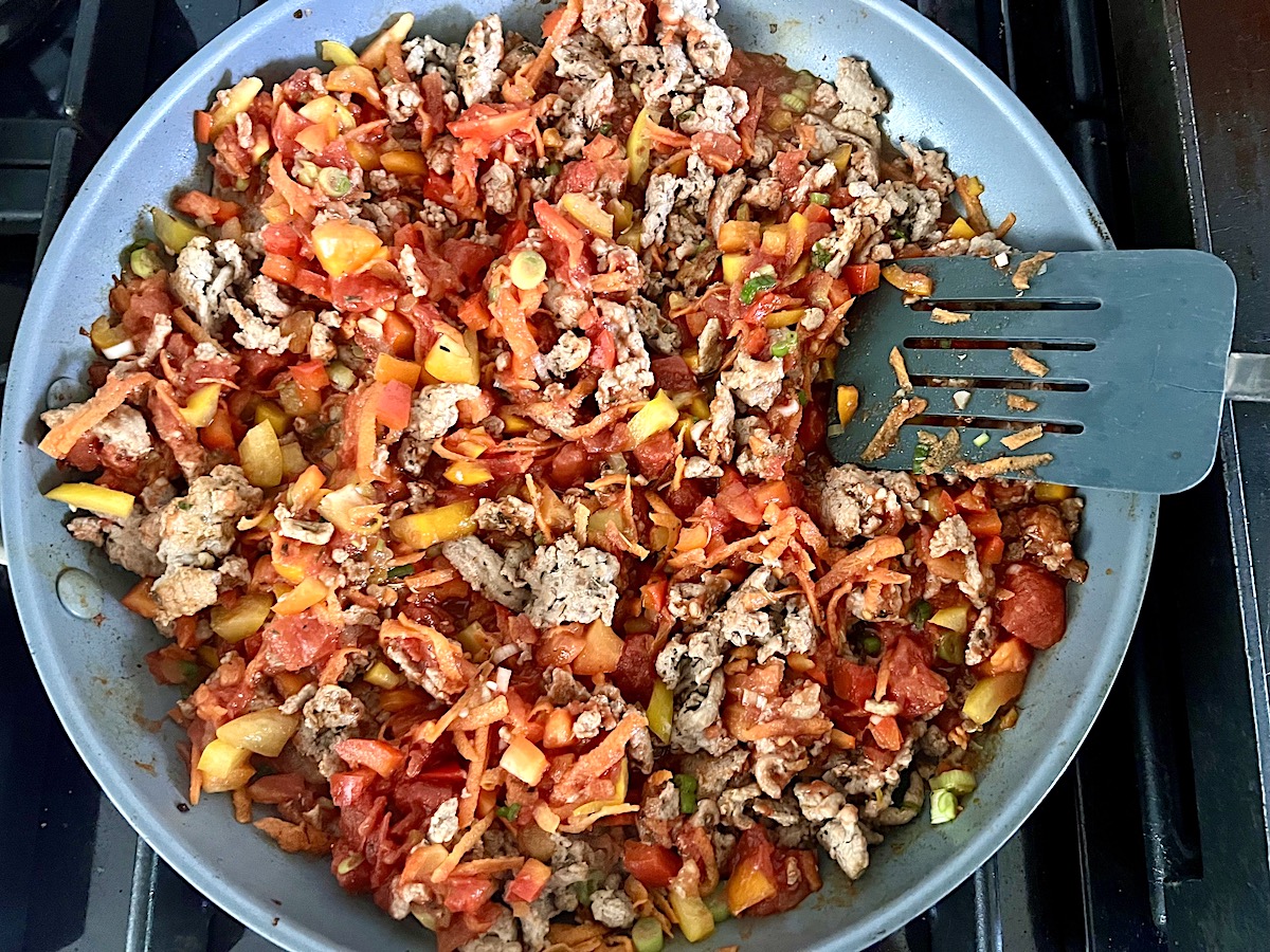 Ground turkey cooking in a frying pan with diced peppers for the Stuffed Peppers with Ground Turkey recipe.