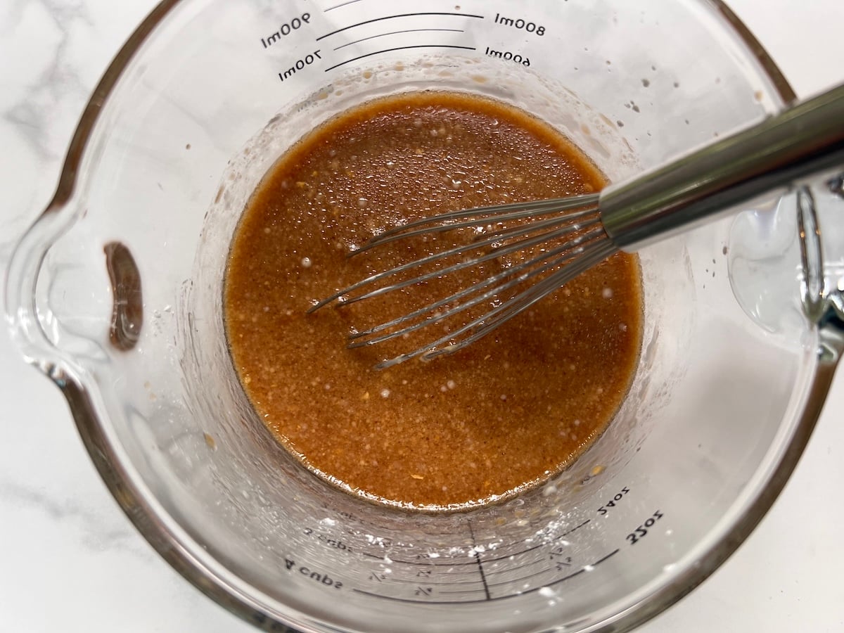 Sauce in clear glass measuring cup with whisk for this Chicken Stir Fry Recipe.