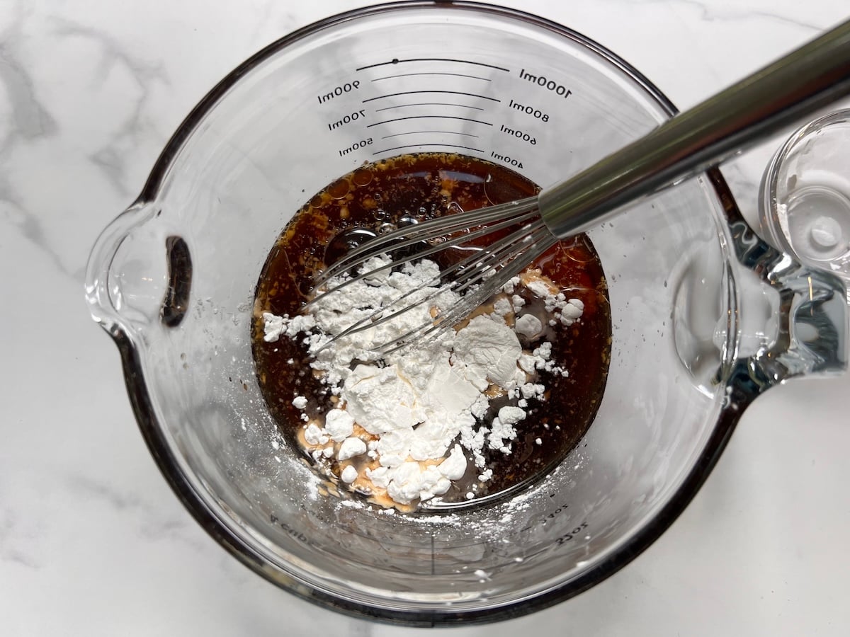 Sauce with cornstarch added on top in clear glass measuring cup with whisk for this Chicken Stir Fry Recipe.