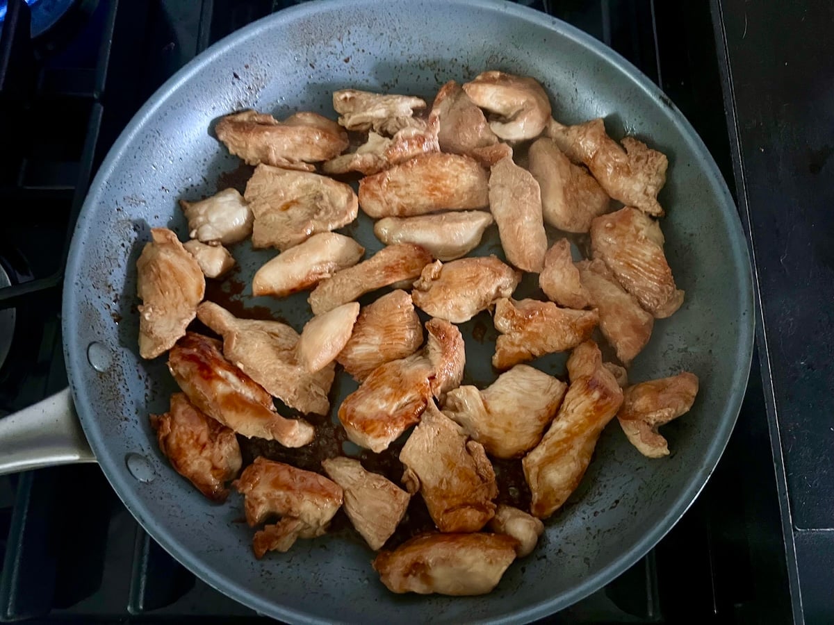 Marinated chicken strips cooking in a skillet for this Chicken Stir Fry Recipe.