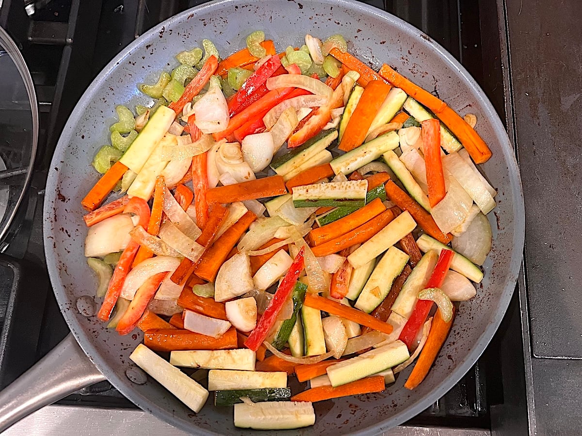 Sliced zucchini, red pepper, celery, onions, and carrots cooking in the skillet for this Chicken Stir Fry Recipe.