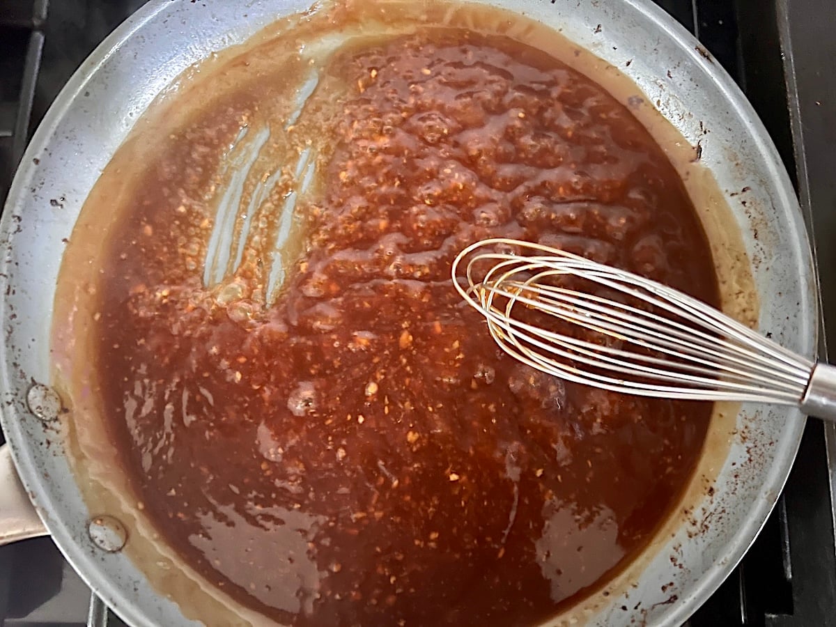 Sauce thicked in pan with whisk showing sauce tracks in the pan for this Chicken Stir Fry Recipe.