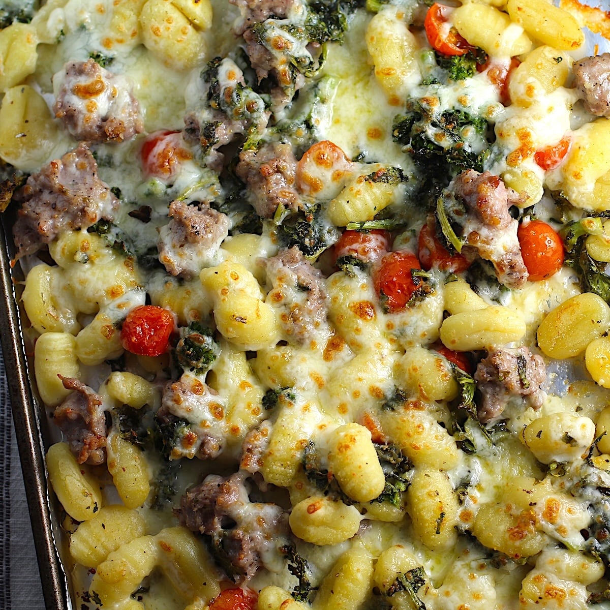 Sheet Pan Gnocchi, Italian Sausage, Broccoli Rabe, and Cherry Tomatoes golden brown with melted mozzarella on top.