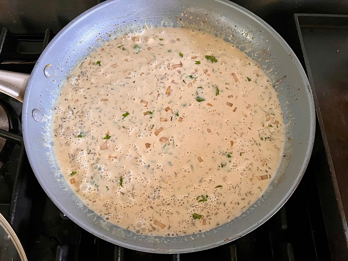 Whisking broth and cream or half and half to shallots and dijon in pan Finely diced shallots cooking and browning in the pan after the chicken is transferred out for the Chicken au Poivre recipe.