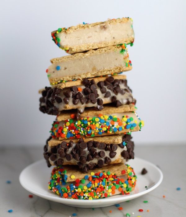 Banana Ice Cream Sandwiches with Sprinkles and chocolate chips stacked on top of each other. Banana Ice Cream is literally just 2 ingredients, Frozen Bananas and Almond Milk.  Add in crunchy Graham Crackers as the 3rd ingredient and you have a delicious healthy Banana Ice Cream Sandwich! 