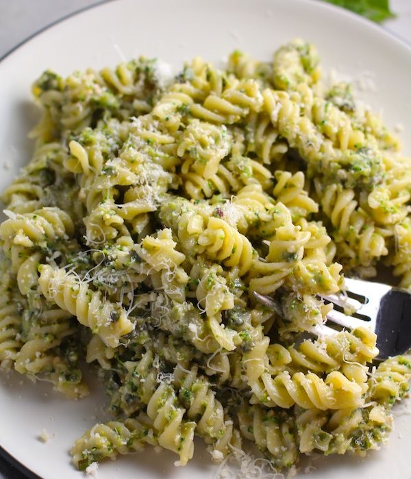 Broccoli Pesto Pasta on a plate with fork in pasta. It's delicious AND good for you!  It has all of the classic pesto flavors from garlic, basil, parmesan cheese, and pine nuts.  But the flavor is a bit more mellow by adding broccoli! #broccolirecipes #pesto #pasta #easydinner #dinnerideas #familydinner