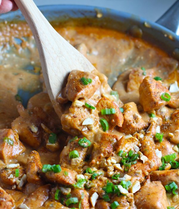 Quick Cooking Creamy Chicken Paprika in a frying pan with wood spoon and scallions and chopped cashews on top. It's creamy, smokey, rich, and hearty. This is an easy weeknight family dinner!
