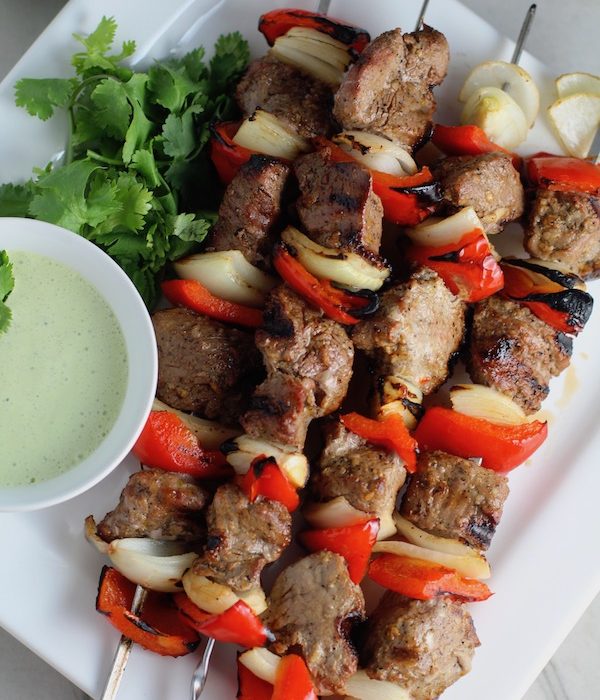 Garlic Steak Kabobs with red pepper and onion on platter with a Creamy Cilantro Sauce! #beefkabobs #steakkabobs