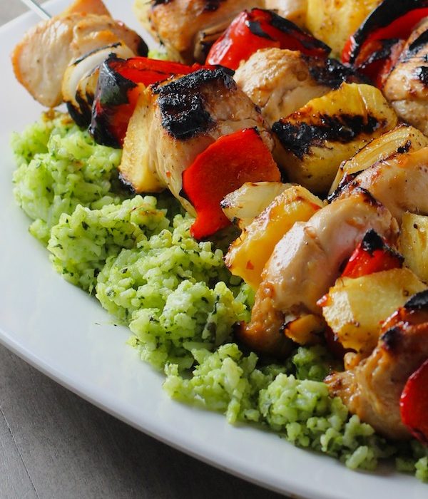 Green Rice on platter with chicken kabobs on top. This Recipe takes white rice from plain to amazing with just 5 ingredients. Filled with herbs and spinach, it has the perfect herby flavor.