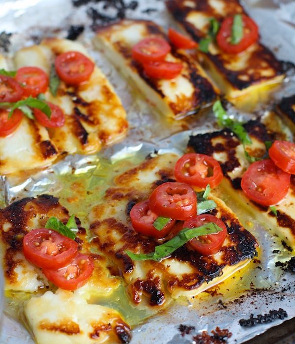 Grilled Halloumi Cheese & Tomato Salad on pan. It's insanely delicious! Grilled Halloumi has a strong savory and salty flavor that is slightly creamy and incredibly addictive. Paired with my simple Tomato and Basil salad, each bite is simply heaven. #halloumi #appetizers #salads #grilling #summerfood