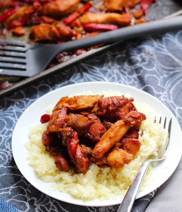Hoisin Chicken over rice on a plate with a fork. In back is pan with spatula. This Freezer Hoisin Chicken with Red Peppers, Carrots, Onions, Ginger, and Soy sauce is delicious and so easy to make. You get sweet and savory all in one dish and it's perfect for kids because it's sweet, not spicy at all. Just freeze ahead, thaw, then cook on a sheet pan!