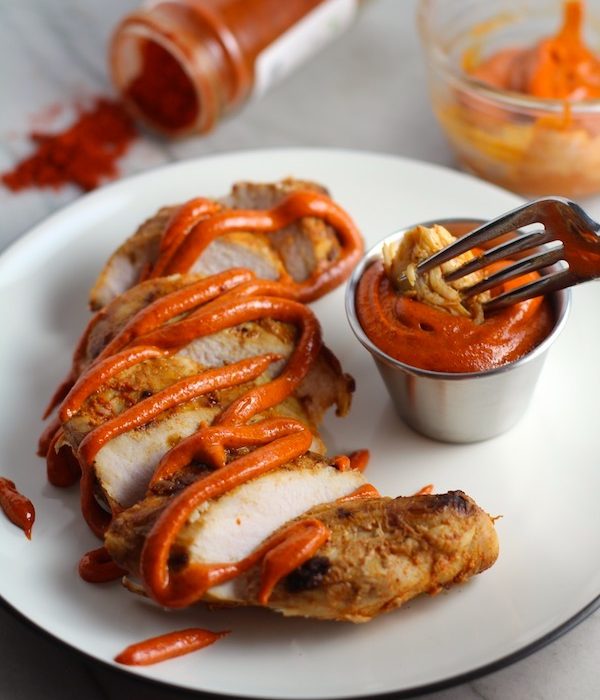 Hungarian Paprika Chicken sliced on plate with Paprika Aioli drizzled on top and fork dipping a bite. The paprika gives beautiful color and a deep, peppery flavor. #chicken #easychicken #easydinner #dinner #healthydinner
