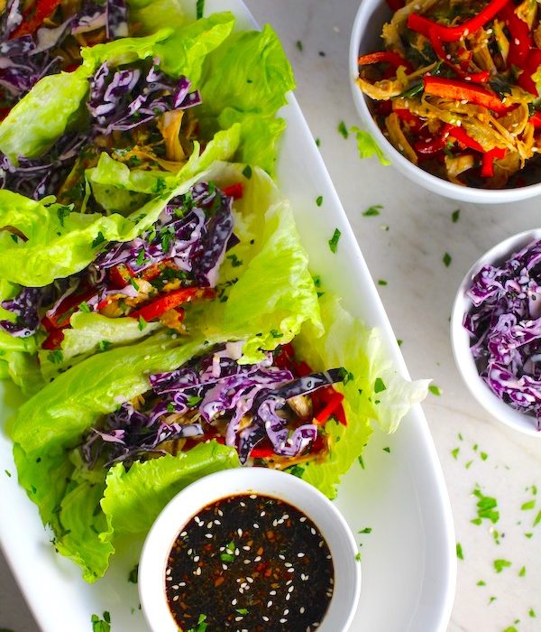 Asian Lettuce Wraps on a plate with sauce. They are a fantastic way to use leftover Turkey or Chicken transforming it with new delicious flavors and textures. The turkey is stir fried with carrots, red pepper, and brussel sprouts in a flavorful ginger, garlic, & sesame sauce. It's layered in lettuce wraps with rice and a cool, crunchy purple cabbage sesame slaw. Serve with a Garlic Honey Soy Sauce....YUM!!!