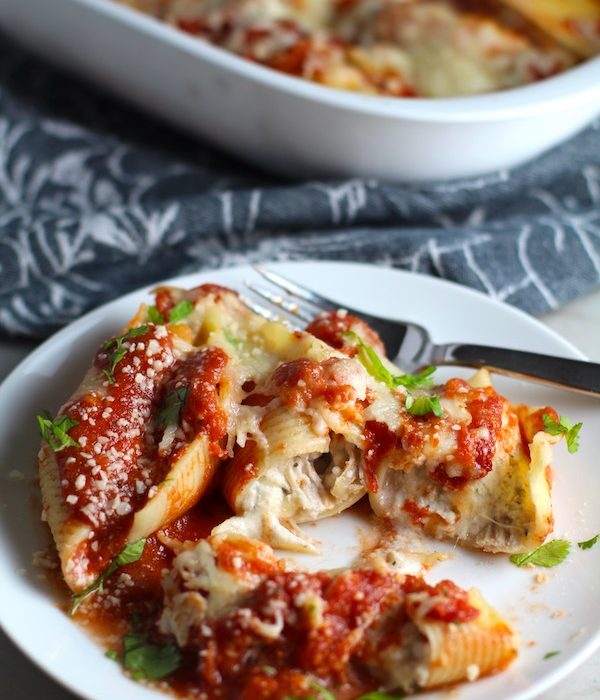 Turkey Ricotta Stuffed Shells in Tomato Sauce on plate cut with casserole dish in background. These are the perfect way to repurpose and transform leftover Turkey or Chicken. The Shredded Turkey, Italian seasonings, mozzarella, and ricotta are stuffed in shells and topped with a simple tomato sauce and more melty mozzarella and nutty parmesan, it's a perfect dish that the family will love!