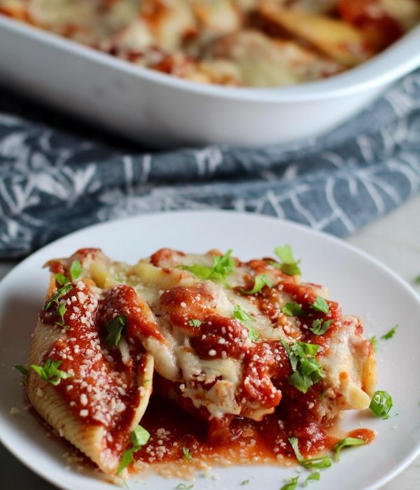 leftover turkey pasta bake Stuffed Shells in Tomato Sauce on plate with casserole dish in background. These are the perfect way to repurpose and transform leftover Turkey or Chicken. The Shredded Turkey, Italian seasonings, mozzarella, and ricotta are stuffed in shells and topped with a simple tomato sauce and more melty mozzarella and nutty parmesan, it's a perfect dish that the family will love!